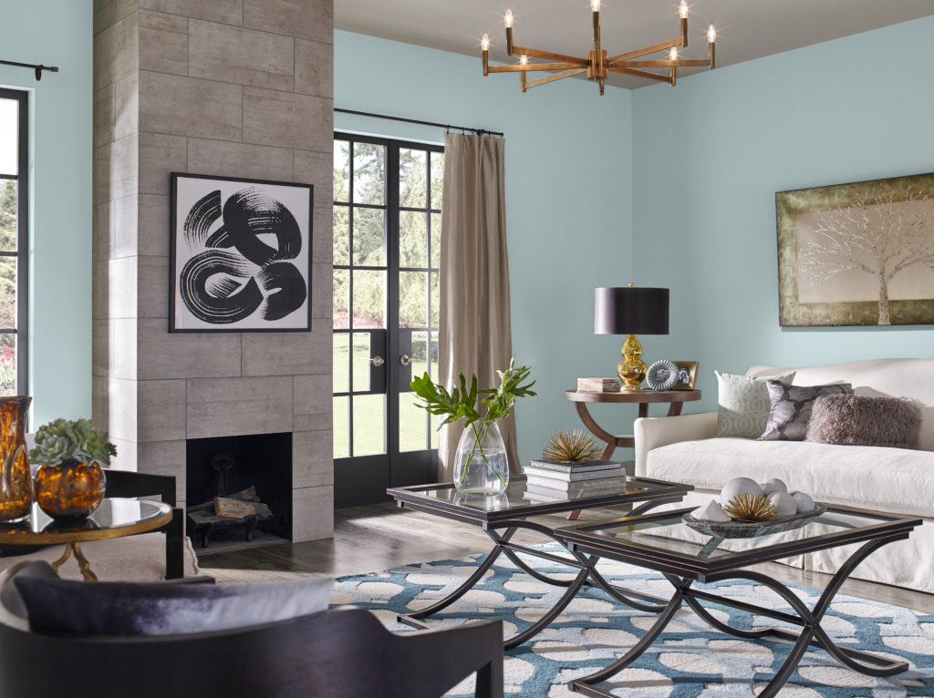 A modern-eclectic decorated  living room with dark natural wood tone furniture,  wall décor elements. The color featured on the wall is called Dayflower. 