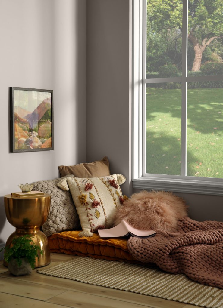 A carved corner in the home that has been turned into a "sheltered" area for relaxing. There is a large window that allow light into the room.  The color on the wall is a light neutral called Doeskin Gray. 