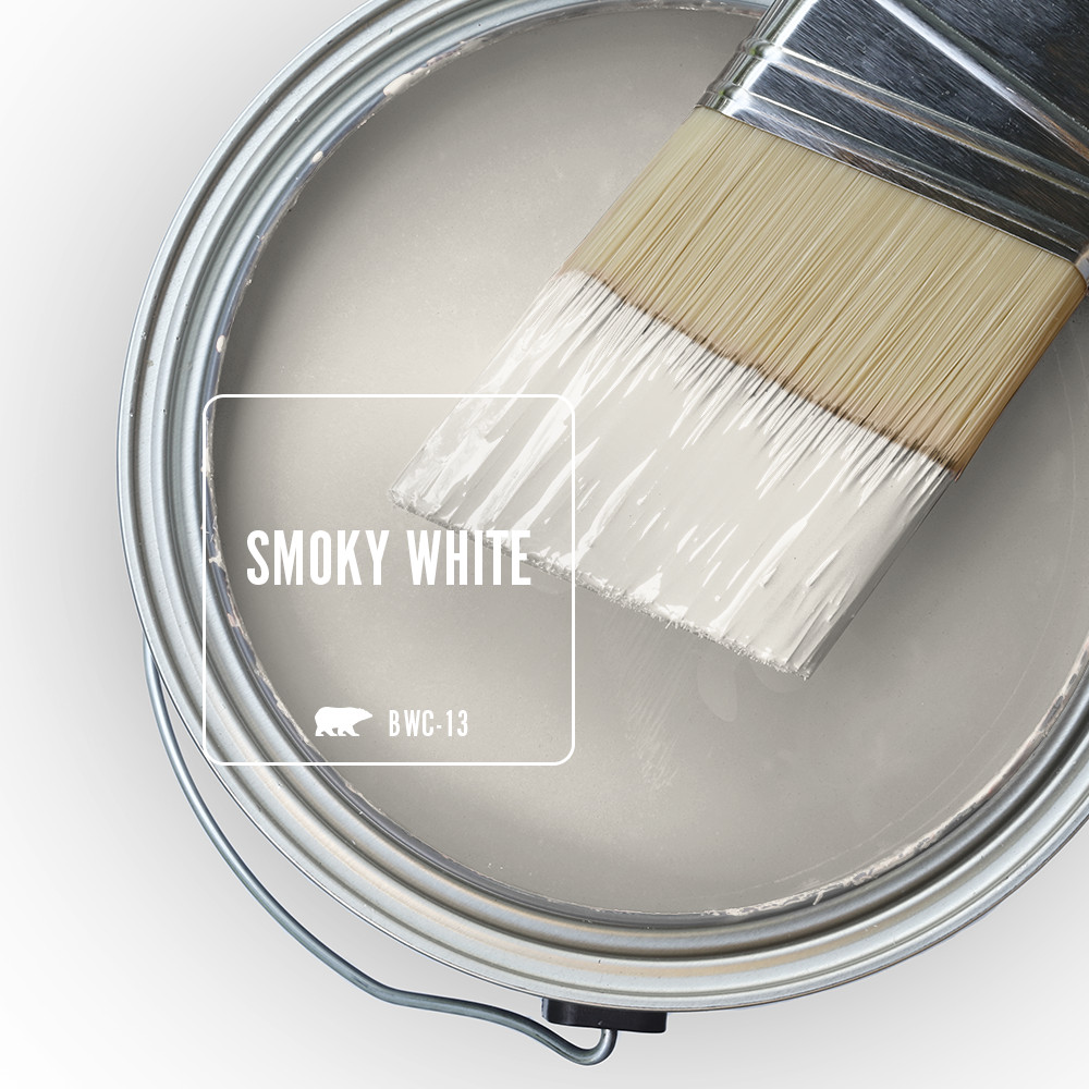 The top view of a paint can with a half dipped paint brush, the liquid paint inside the can is an off-white color called Smoky White. 