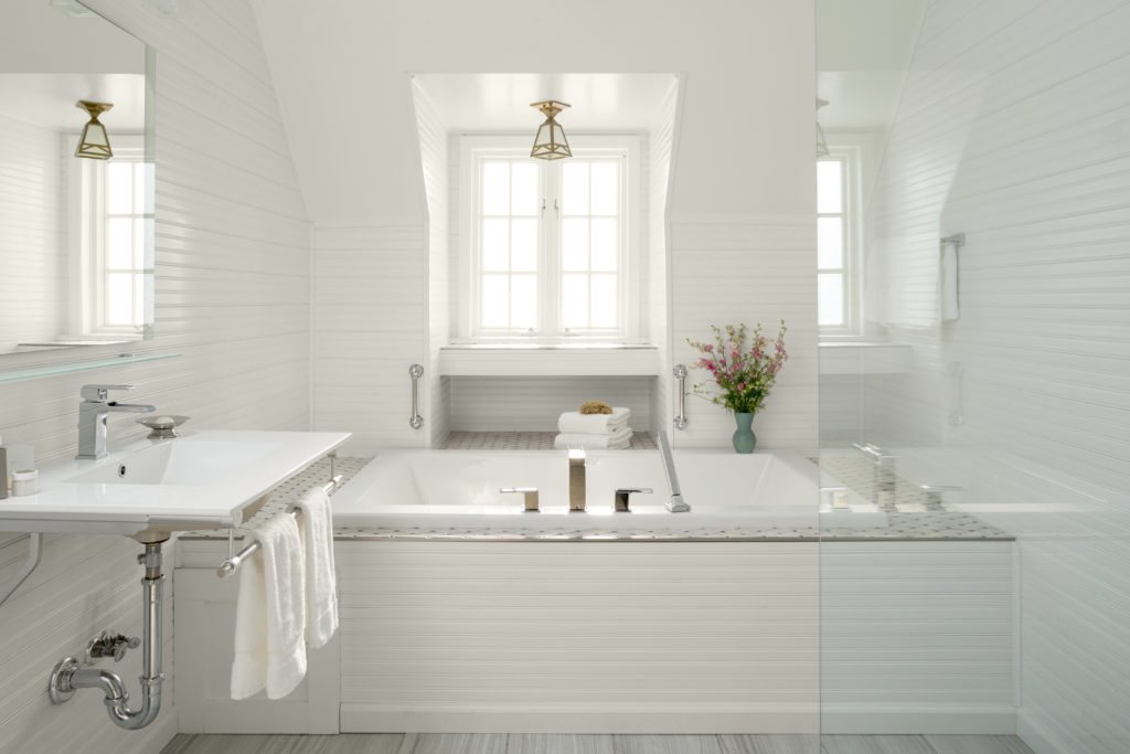 Cottage Style bathroom, the bead board on the wall is painted in all white paint. The bathtub and tile are also white. 