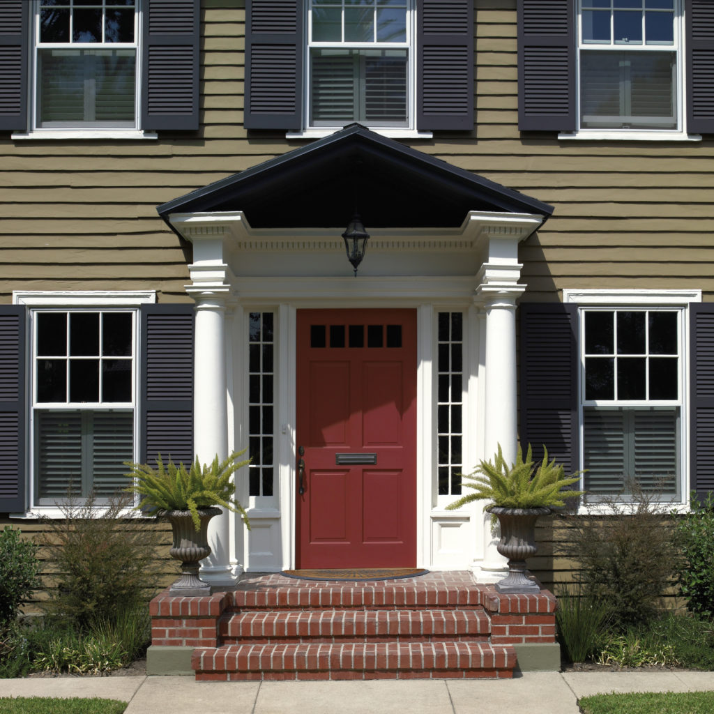 A green painted house with a red front door.