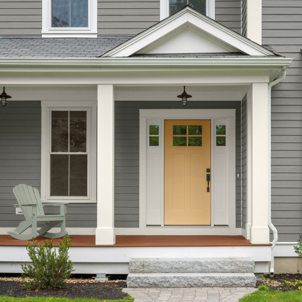 A gray house with a yellow painted front door.