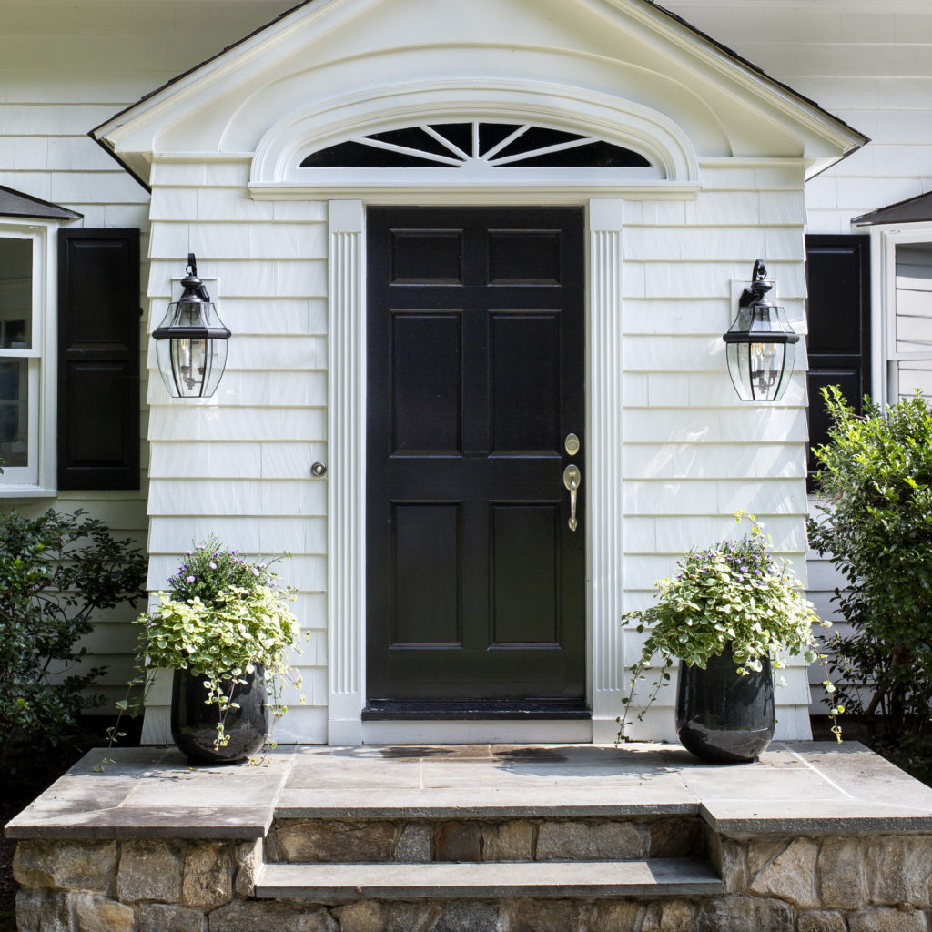 A white colored house with a black painted door.