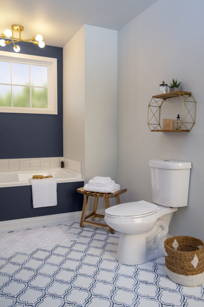 A vertical shot of the newly designed bathroom, focusing on the toilet side.  A fun and stylish shelf was added to that side of the wall to create visual interest and to display small plant, essential oils, and other small decorative items. 