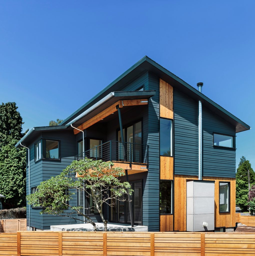 An Exterior Two Story Home with Wooden Mid Century Modern Look, the body of the house is painted in a dark blue color called Nocturne Blue. 