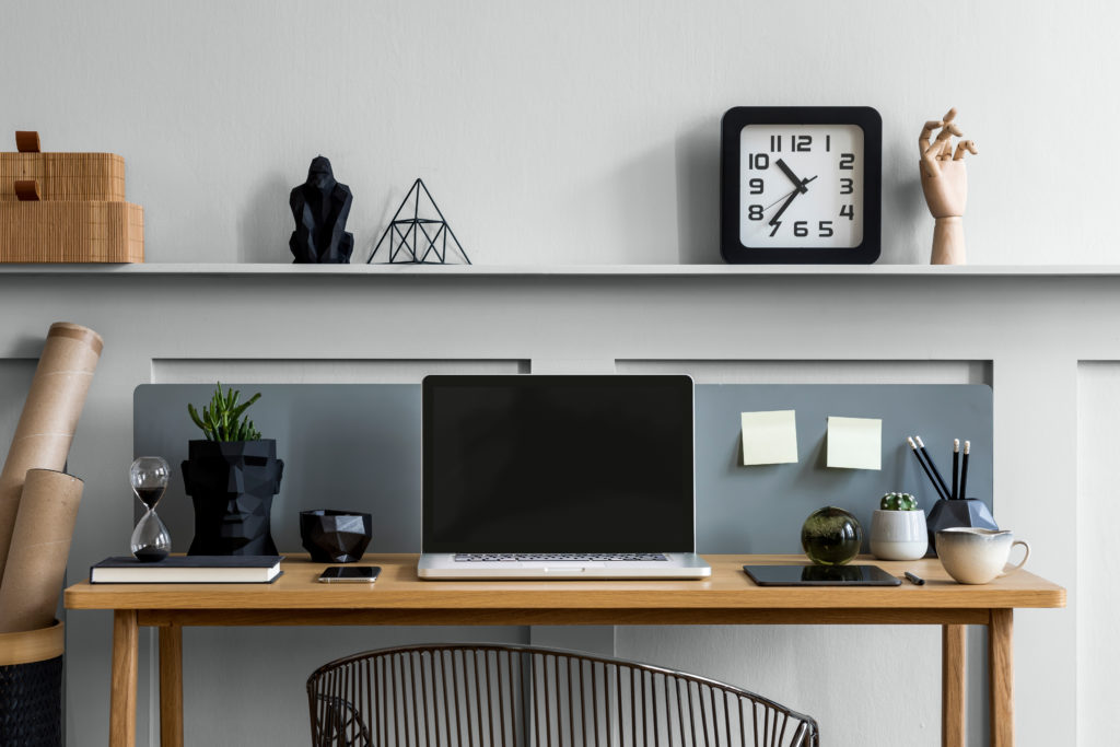 A light gray home office, the  composition on the wooden desk includes a display of  mocked up templates, office supplies and elegant accessories in modern concept.  The color used on the wall is called Platinum.