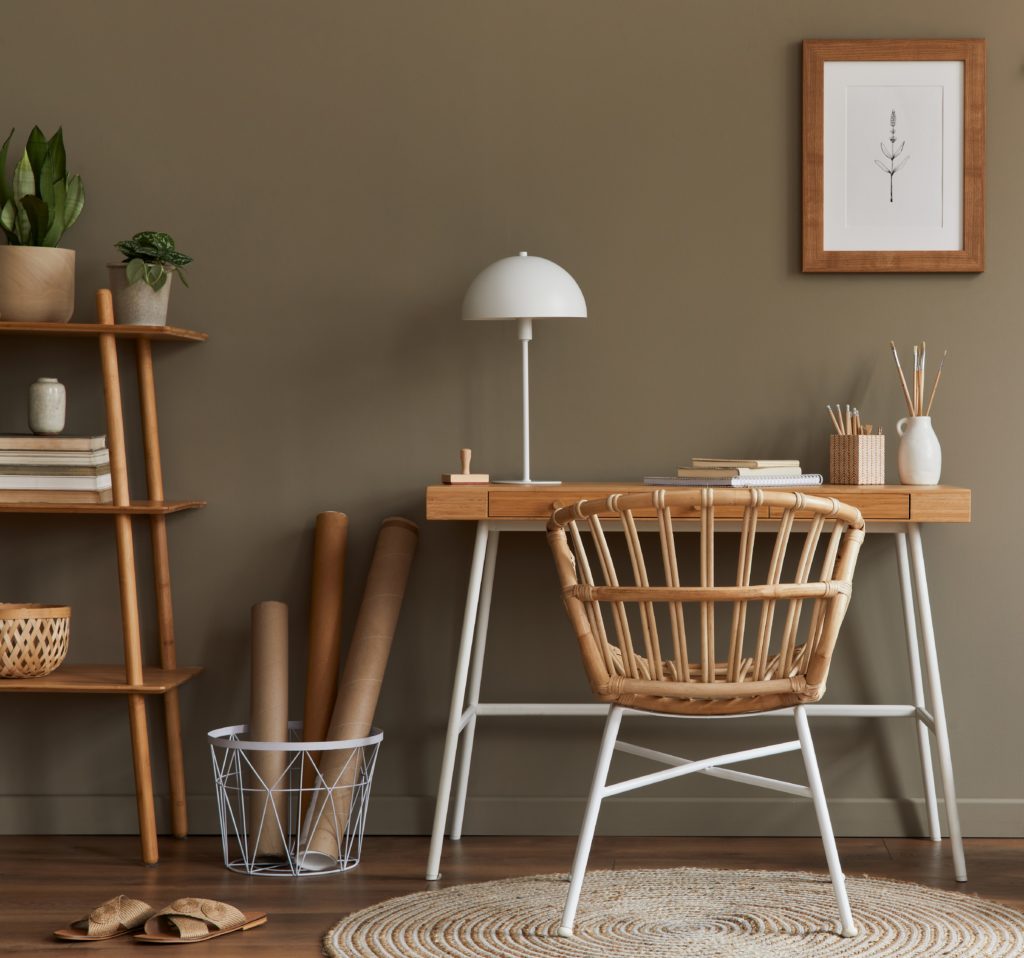 Stylish bohemian interior of home office space with wooden desk, office supplies, decoration and elegant personal accessories in home decor. The mod-to-dark brown color on the wall is called Light Truffle.