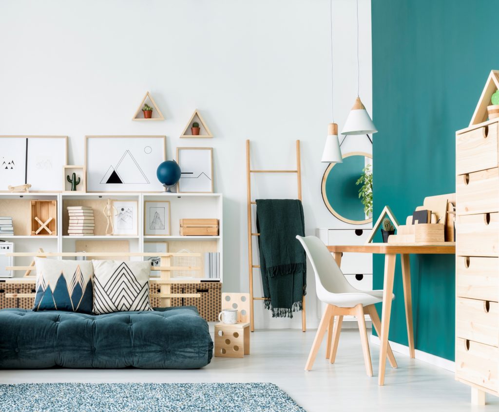 A speckled patterned carpet in white and turquoise colors, A unique bed and mattress in colorful living room interior , there is ao desk area with an accent wall painted in a turquoise color called Thai Teal.