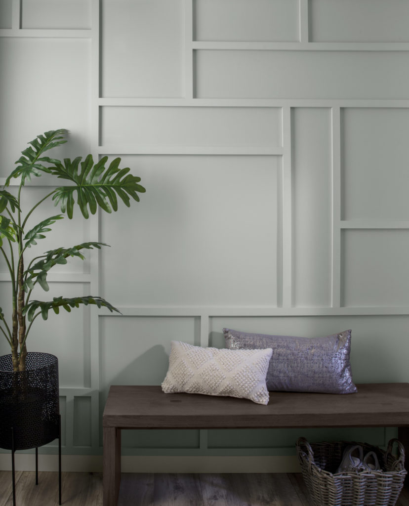 A close up view of a wall that has trim panelling added to create random rectangular and square shapes on a wall.