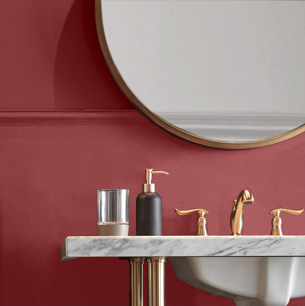 An small and elegant powder room painted in red color called Lingonberry Punch. The hardware is made in a warm metallic color. 