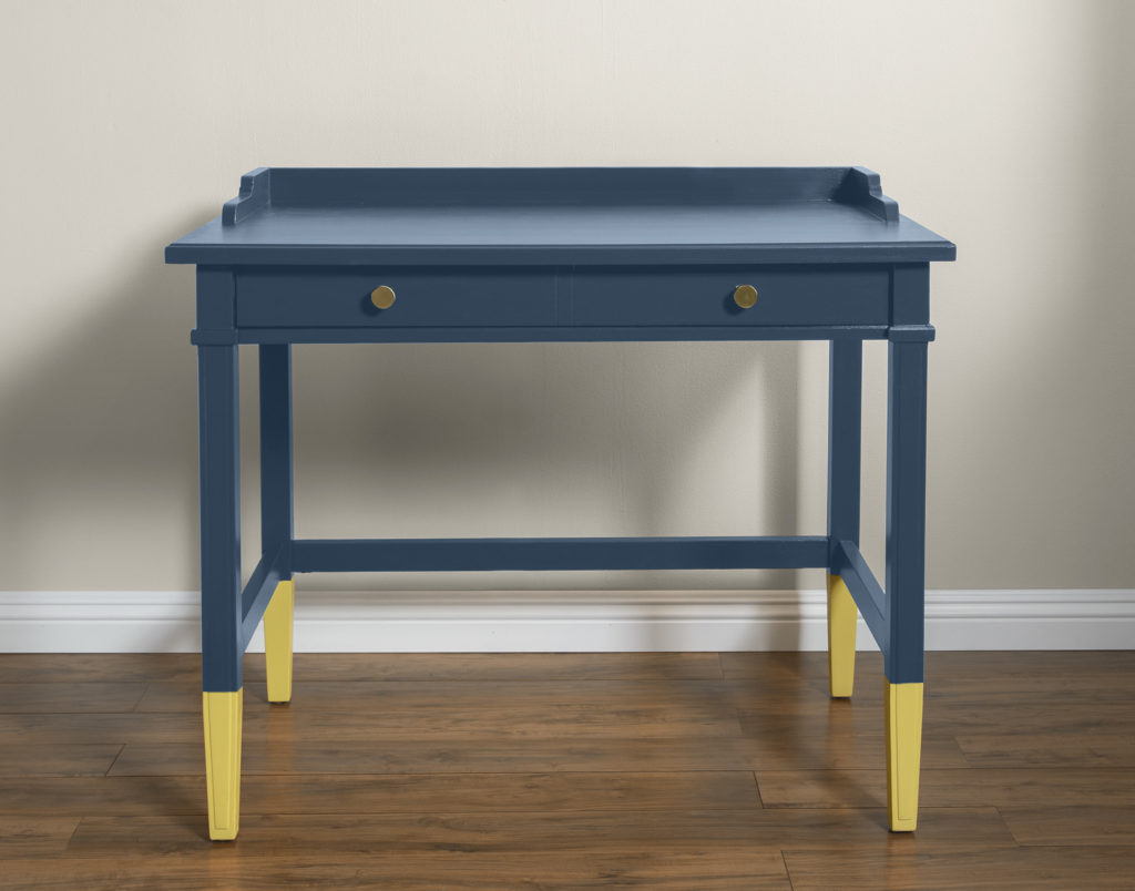 A desk painted in a deep bold blue color with the legs in a vibrant yellow hue.