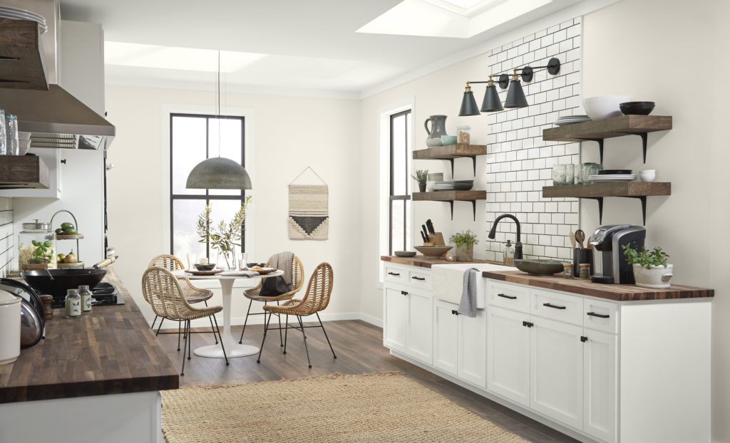 A large modern farmhouse style kitchen, these is small, round dining table and chair on the background.  The color featured on the walls is warm white called, Smoky White. 