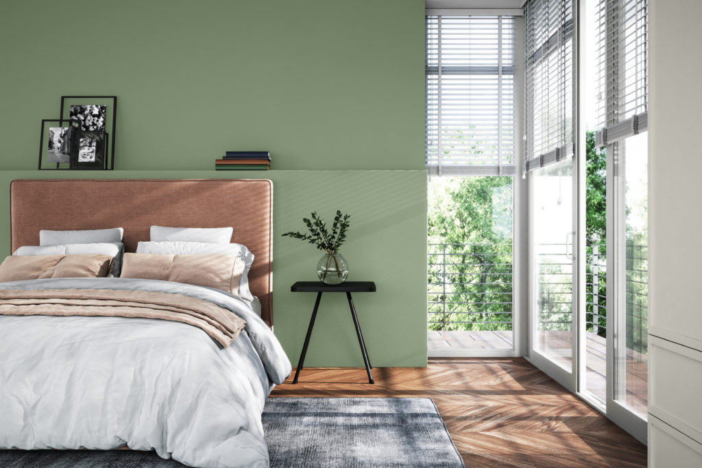 A contemporary interior of bedroom with a lot of natural light, comfy and stylish bed.  There is a green accent wall, the color is called Laurel Tree. 