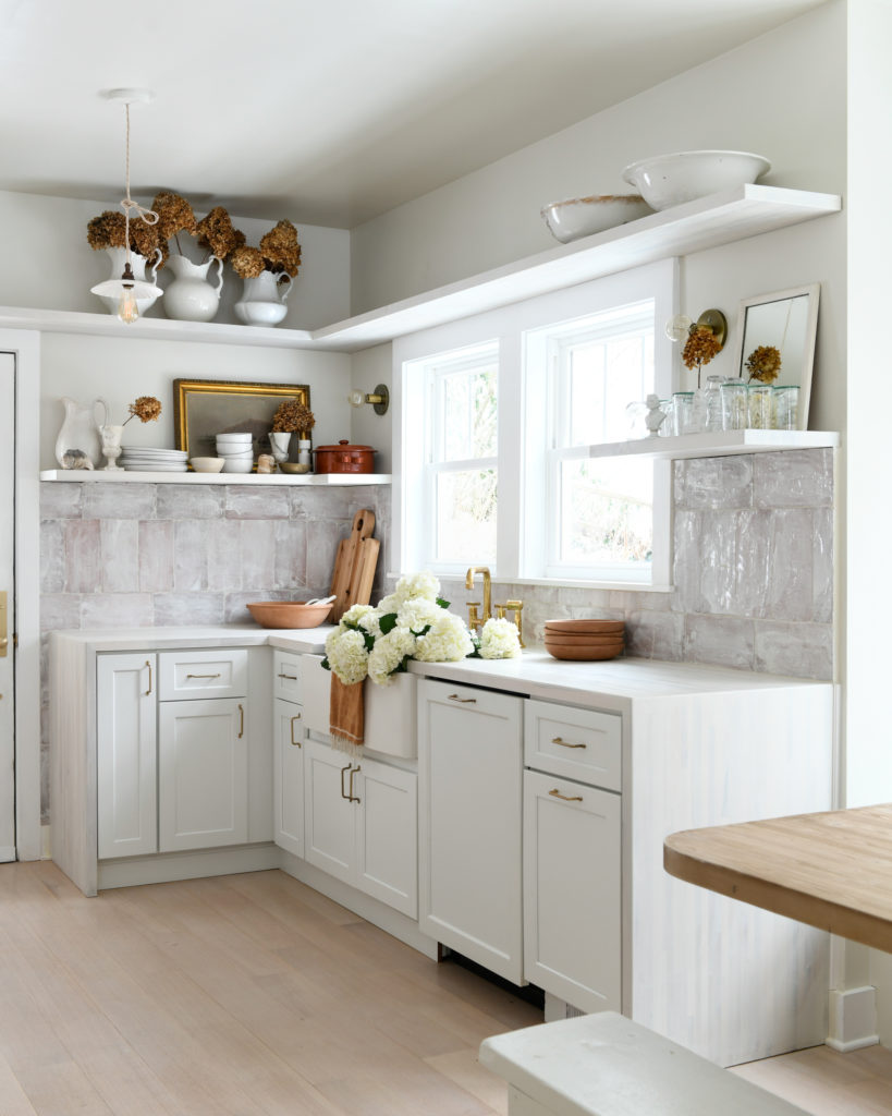 A kitchen in all white hues with wood accents for the table and decor.