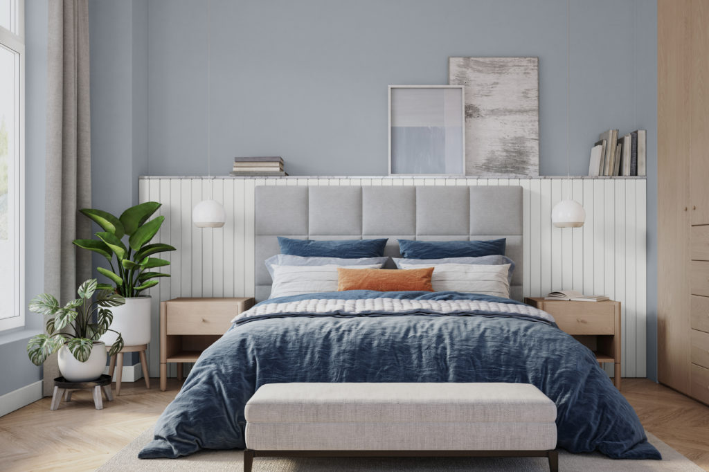 Bedroom image with a stormy blue accent wall in Chance of Rain. Blue furnishings, plants and natural wood tones.