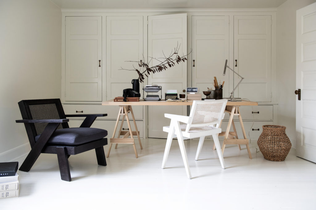 An office with all white hues and also a black chair and wood desk.