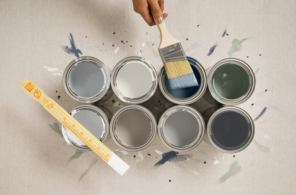 Eight open paint cans with left over paint inside them.