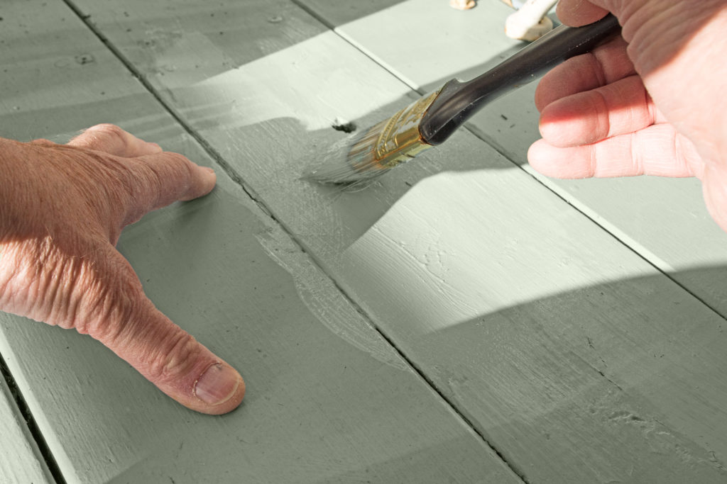 A person touching up paint on floor.