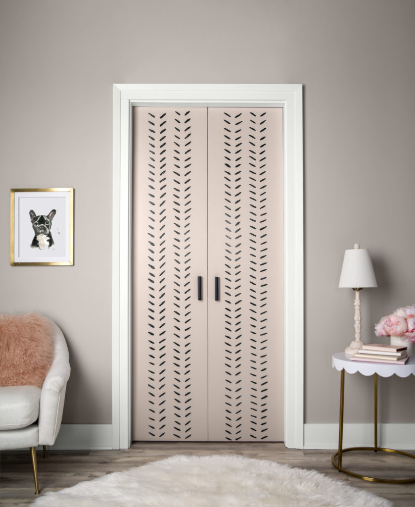 A room with fpucs on the door that is painted in a pink hue with black slashes going up and down in a pattern.