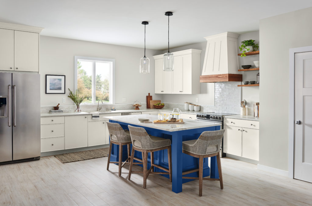 A beautiful neutral kitchen with stainless appliances and dark blue kitchen island which server as a fun focal point and the room.