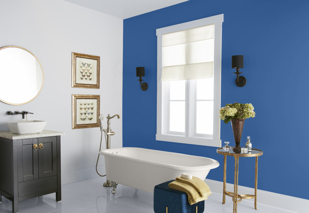 A traditional bathroom with a modern twist.  There is deep blue accent color being featured on a wall, this accent color serves as a bold background  for the clawfoot tub. 