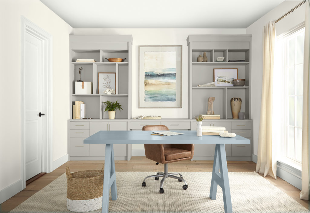 A contemporary home office with painted built-in bookshelves and a painted a desk on the center on the room. 
