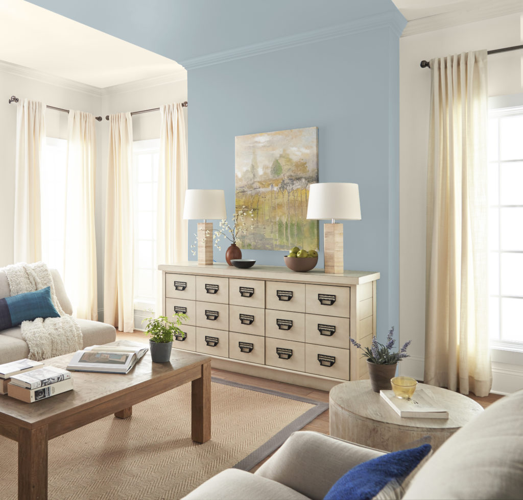 A casual coastal living room with a wall-to-ceiling design painted with a light blue color called Half Sea Fog. 