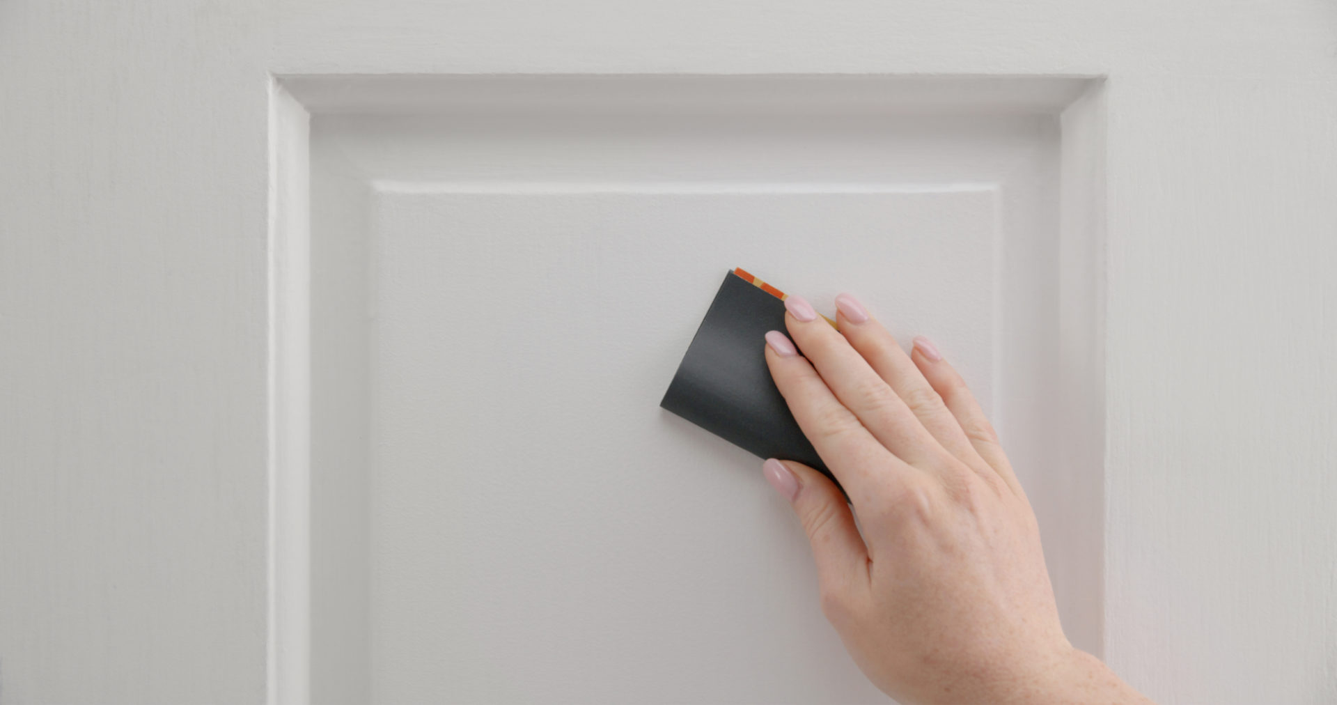 A person using sandpaper on a door.