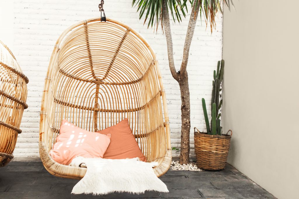 A small outdoor space decorated with Boho outdoor elements, there is a bamboo swing that makes this space extra relaxing and cozy. One wall is painted with Even Better Beige. 