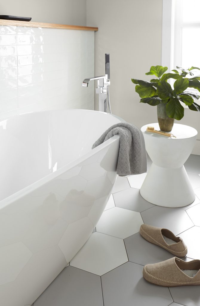A spa like bathroom space with a tube  to take a bath and relax, the walls are painted with Gratifying Gray. There are is white and gray hexagon tiles on the floor. 
