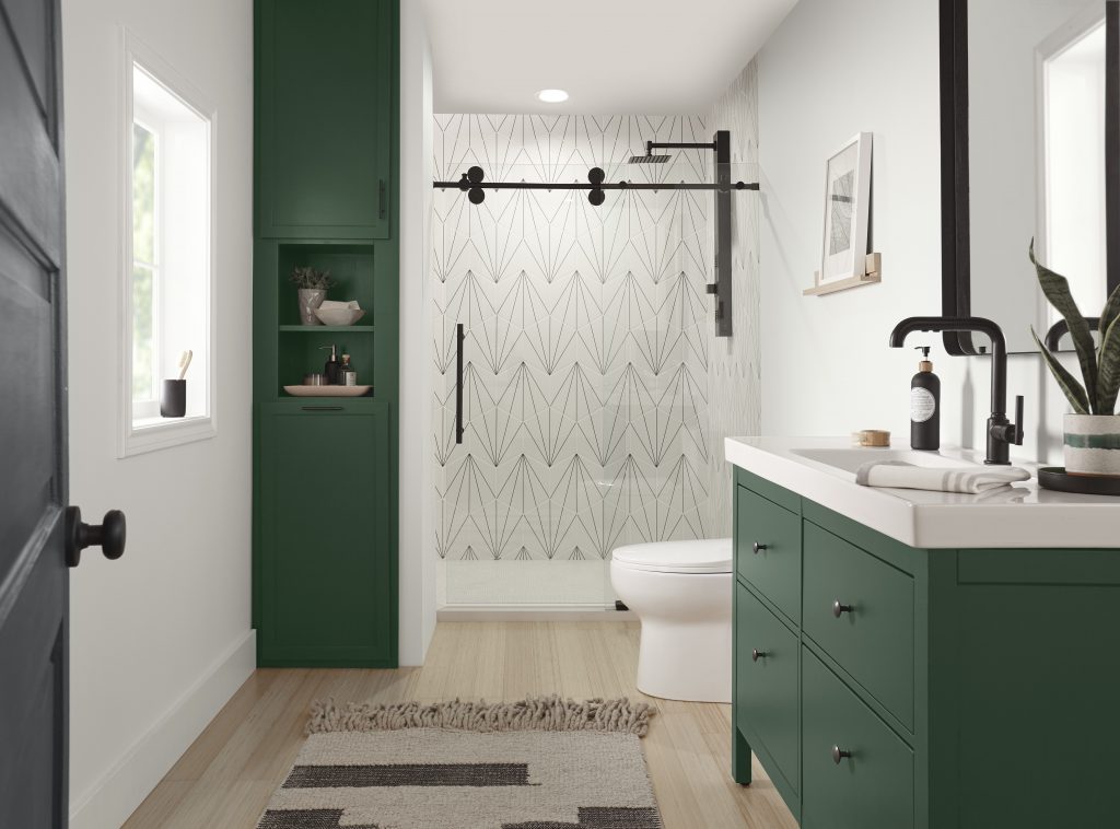 A bathroom with deep green cabinetry and storage.  This room is mostly white with a couple of strategic green and black accents. 