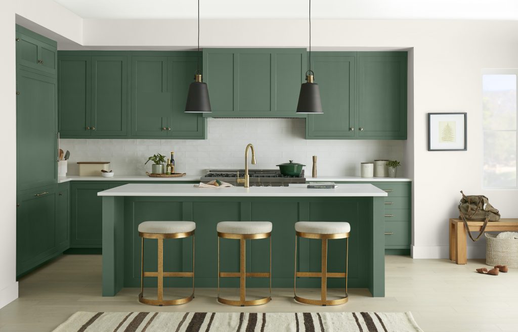A modern chic kitchen with all dark green cabinets and metallic gold hardware. 