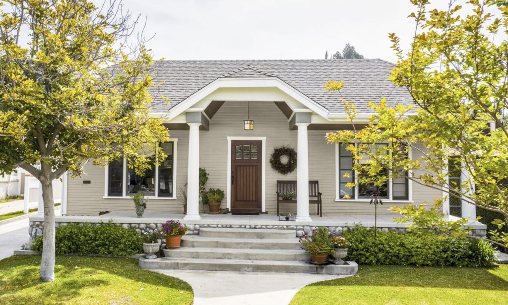 The front view of a southern California home, the architectural style is Craftsman.  The front of the house painted in a light earth tone that is typical of this style. 