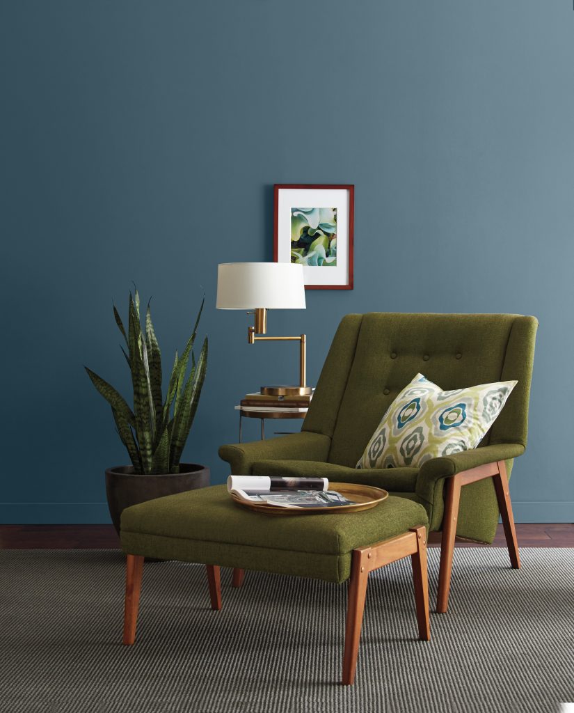 A 70s inspired seating area, featuring a retro chair with  avocado green upholstery. 