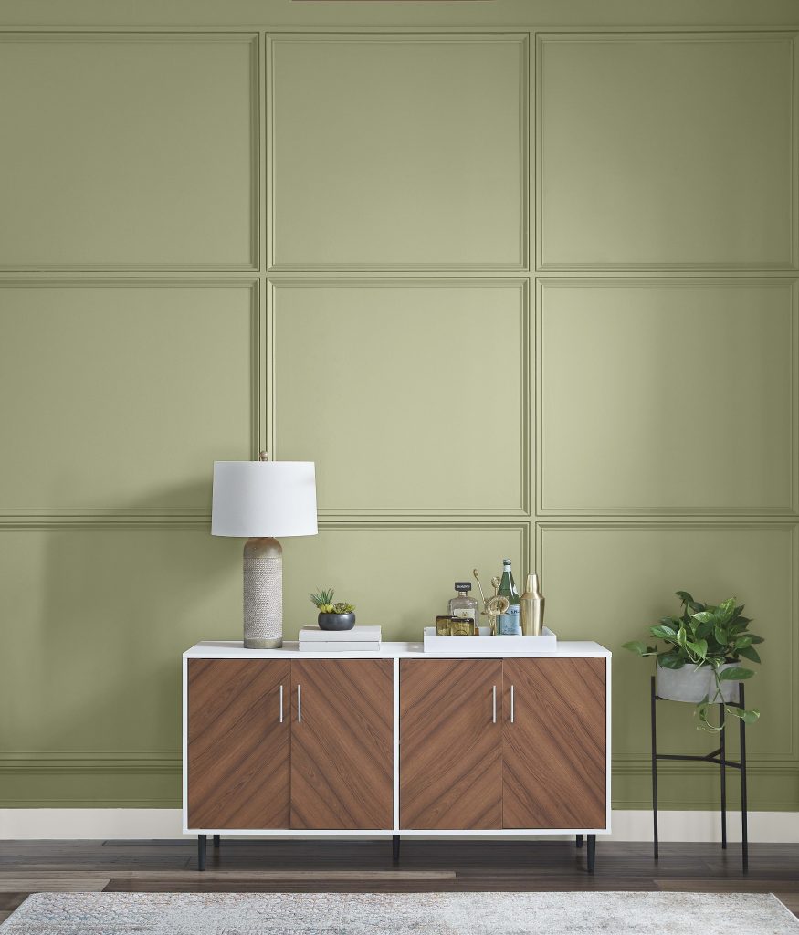 A modern console and lamp place by a decorative wall painted in a mid-tone green color called Sage Brush.