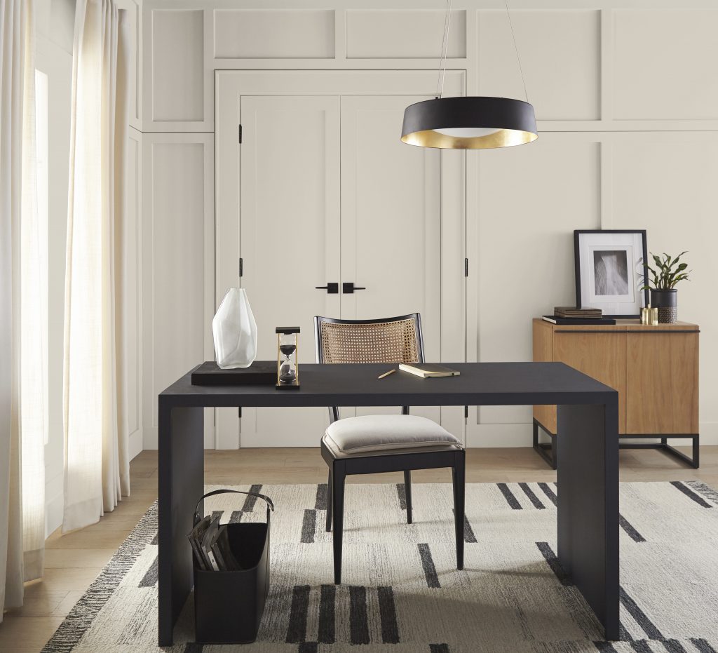 A home office with full board and batten walls painted in Tranquil Gray. The décor is mostly black and has a contemporary feel. Some metallic gold accent give this home office a the finishing sophisticated touch. 