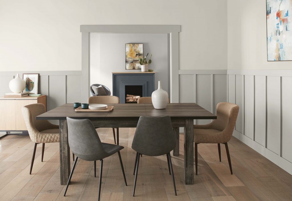 A farmhouse chic dining room with board and batten lower walls. 
The upper wall is painted in the color of the month, Tranquil Gray. 
There is a backroom featuring a fireplace and a small sitting area. 
