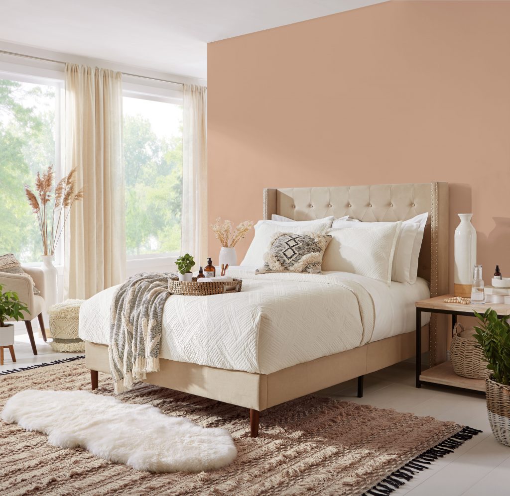 A bedroom with a warm peach color painted in the wall.