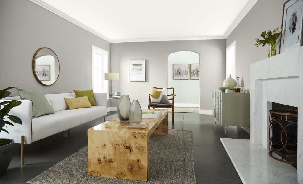 A living room that has a view into the hallway. The room is large and walls are painted in a warm greige hue.
