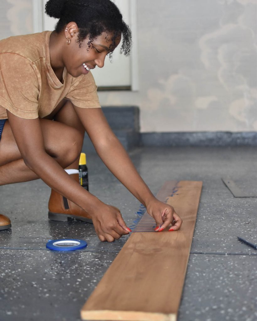 A person placing tape on a wood beam.