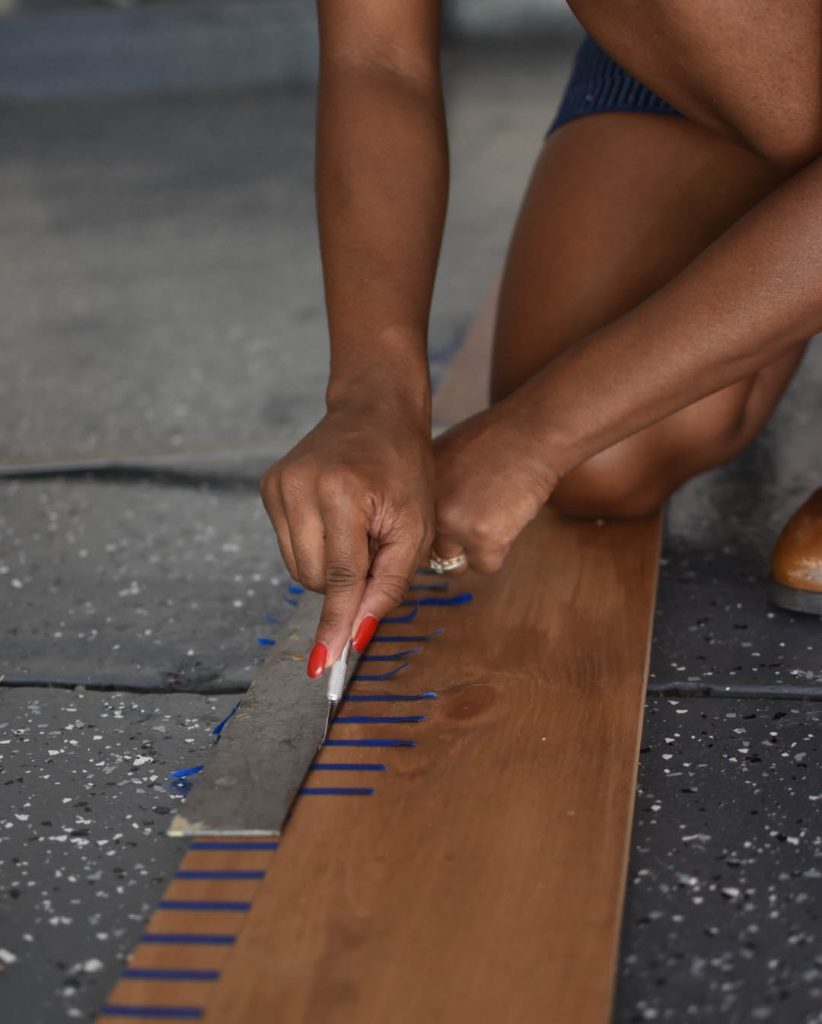 A person using a ruler with an exacto knife to cut a straight line.