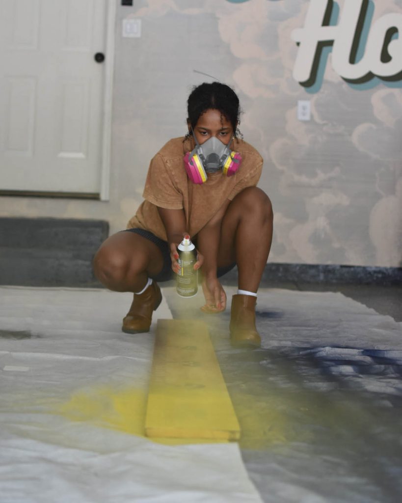 a person spray painting a wood beam.