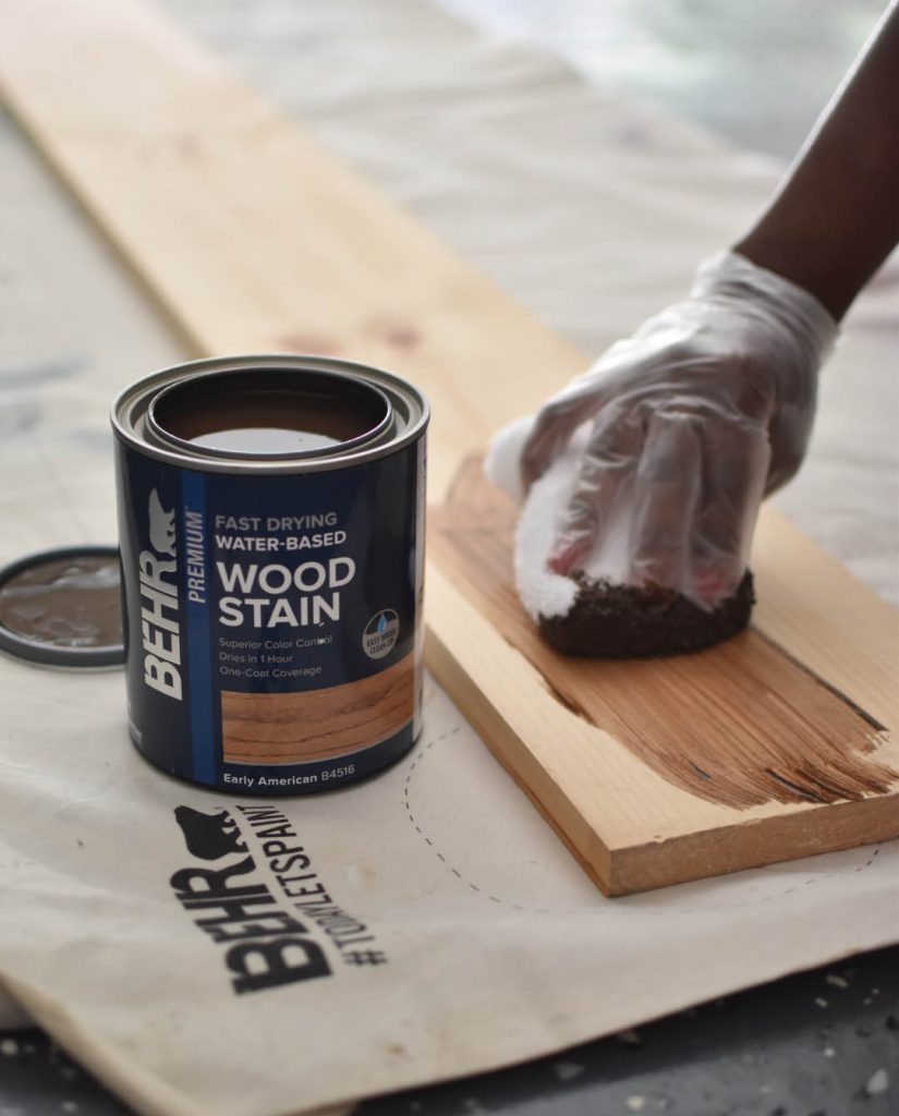A person staining a wood plank.