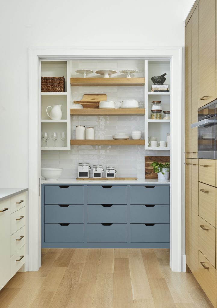 A casual kitchen featuring blue cabinets. The rest of the cabinets and floor are a natural wood tone. 