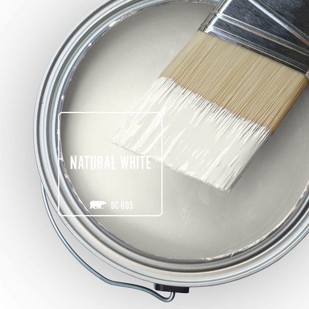 An open paint can with a brush resting on top, showing a white paint color inside.
