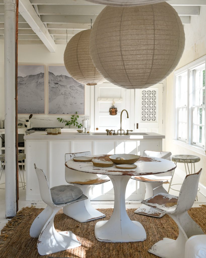 A dining room with rustic furniture and oversized lantern style lights above the table.