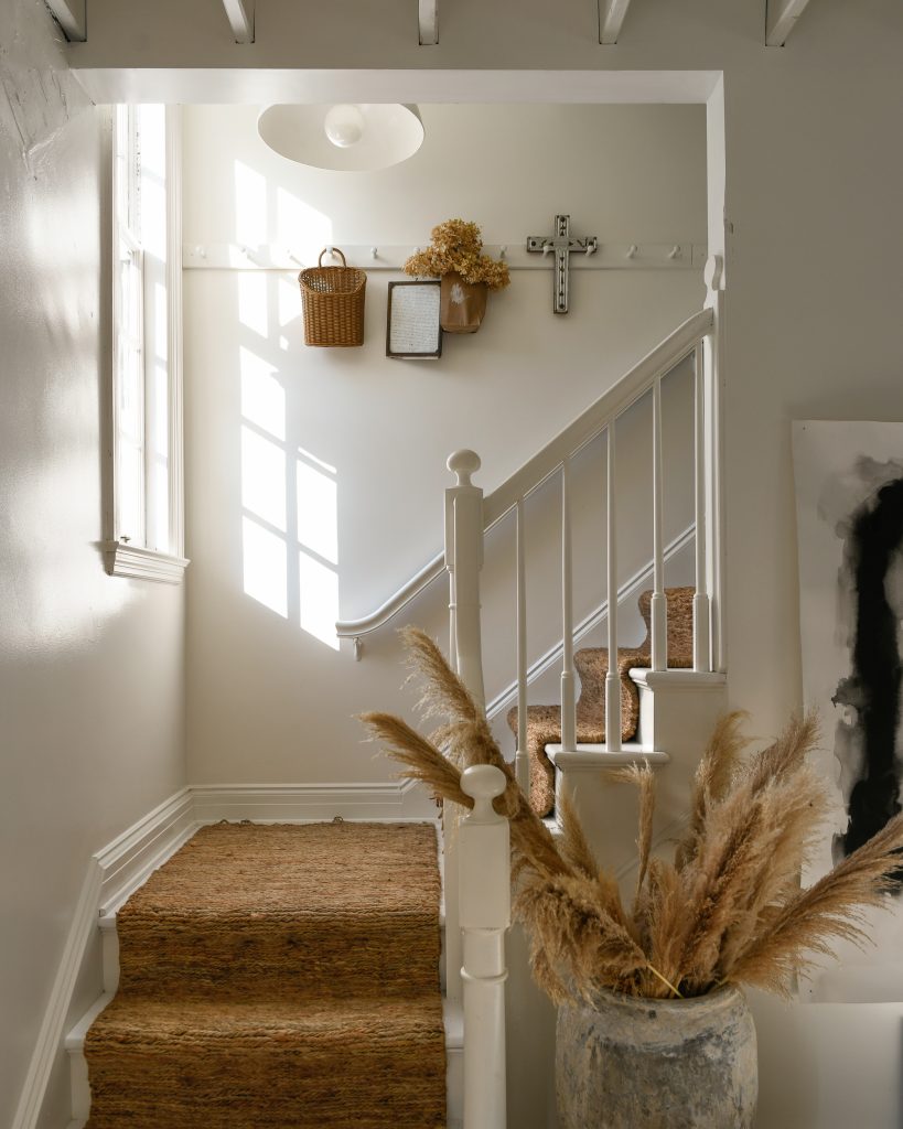 A stairway with the walls painted white and a neutral stair runner.