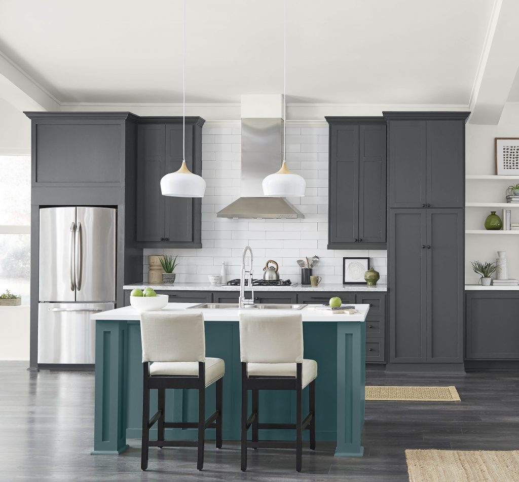A large  modern farmhouse kitchen with dark cabinets and a teal island. The backsplash is white subway tile and the walls are painted in a white color that helps balance out the light in the room. 