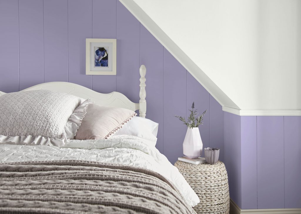A bedroom with the walls painted in a purple hue.