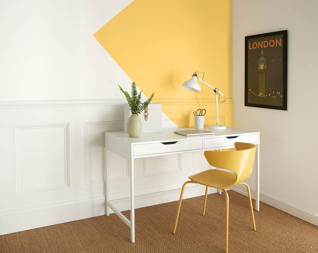An office painted in white with a large yellow triangle painted on the wall coming in from the corner of the room.